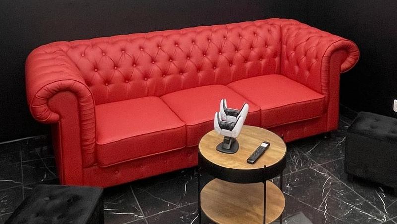 Canapé Chesterfield rouge et poufs noirs dans l'espace d'attente